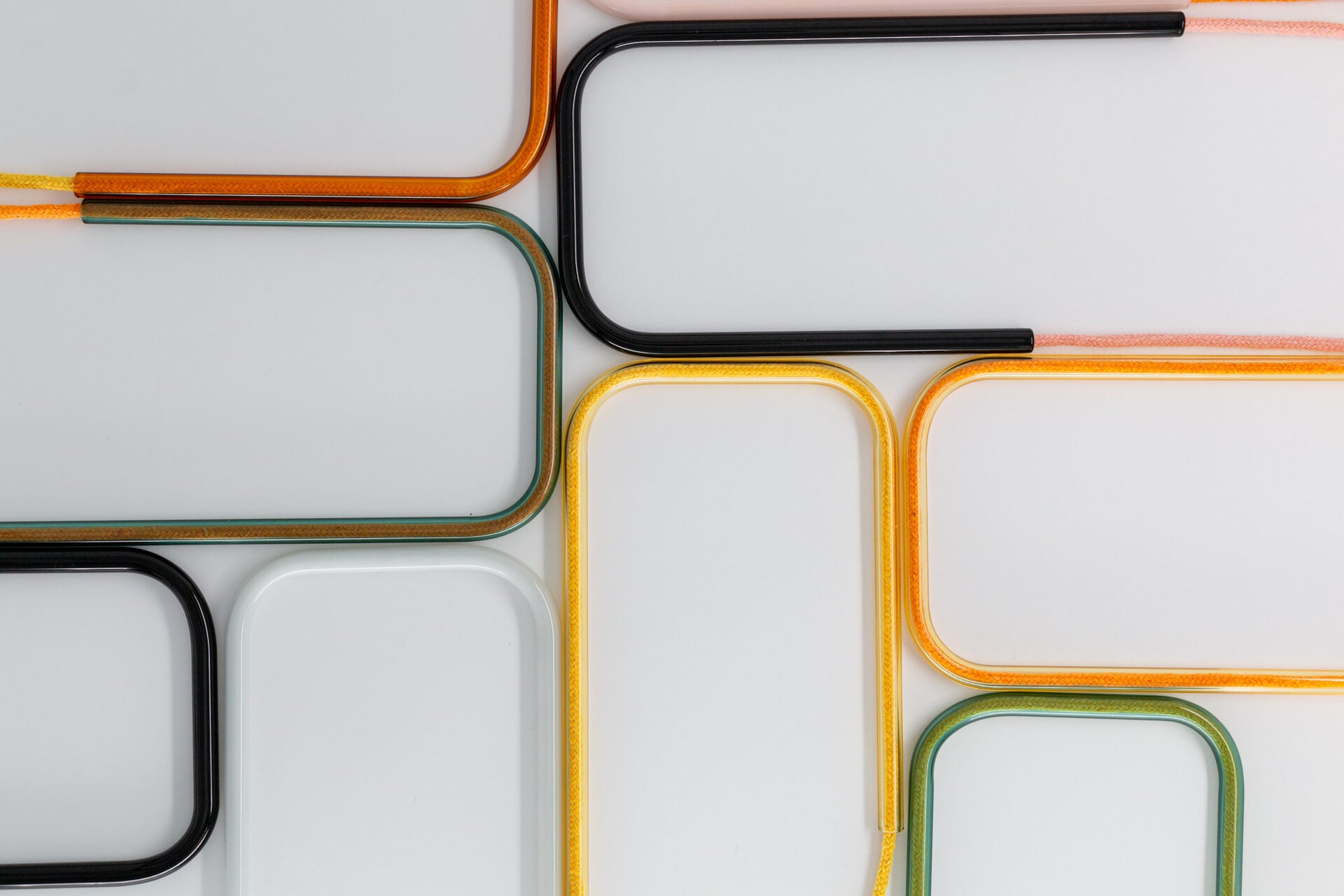 Flat lay view of a colorful collection of glass self-watering indoor plant inserts displayed together in a vibrant variety of design colorways.